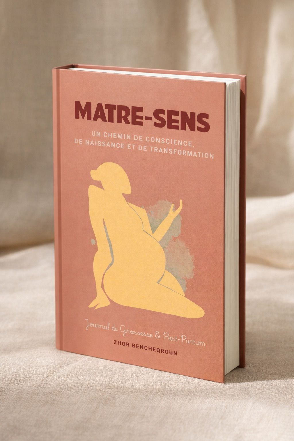 Le livre MATRE-SENS en volume, posé sur un tissu beige